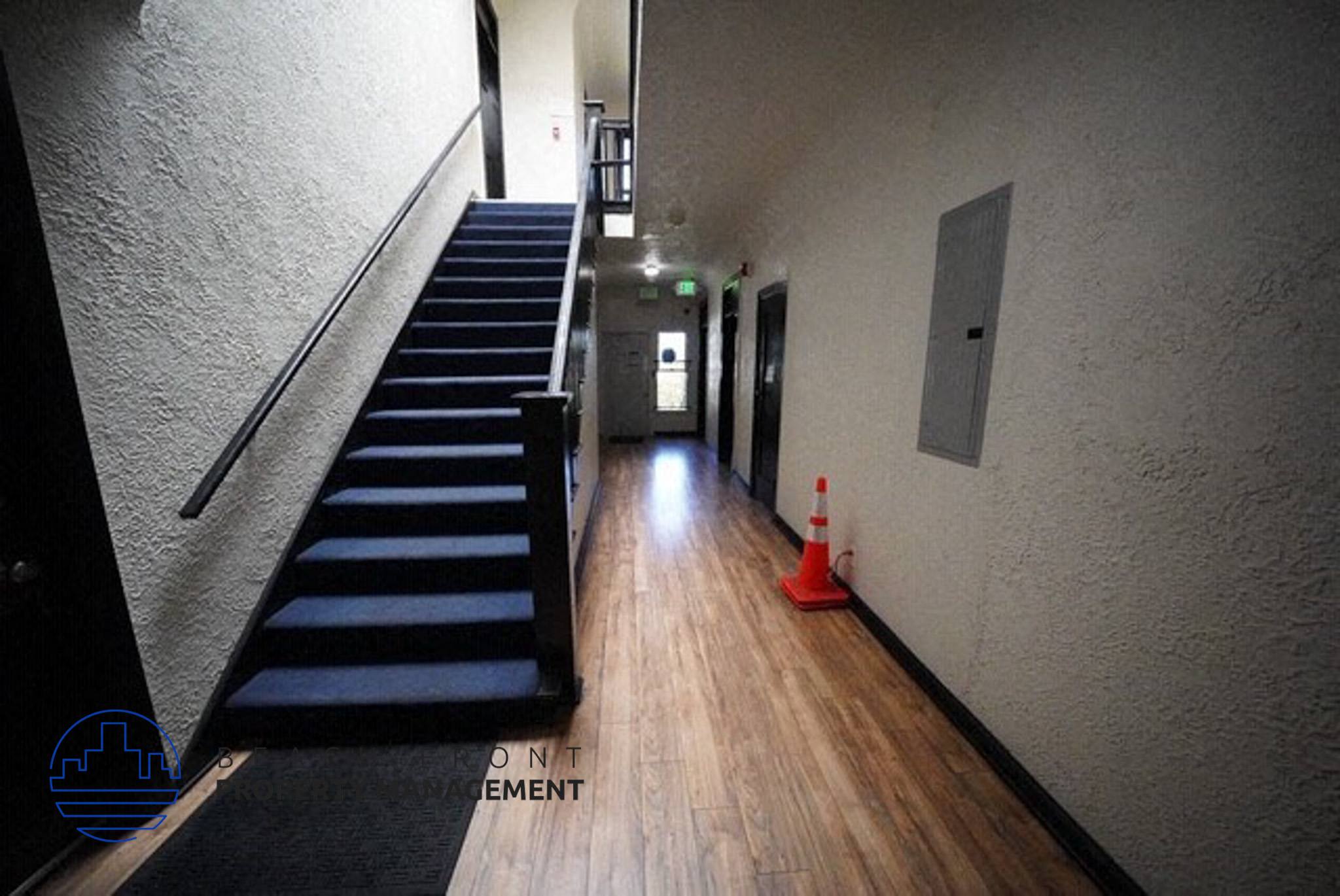 a long hallway with stairs and a black staircase